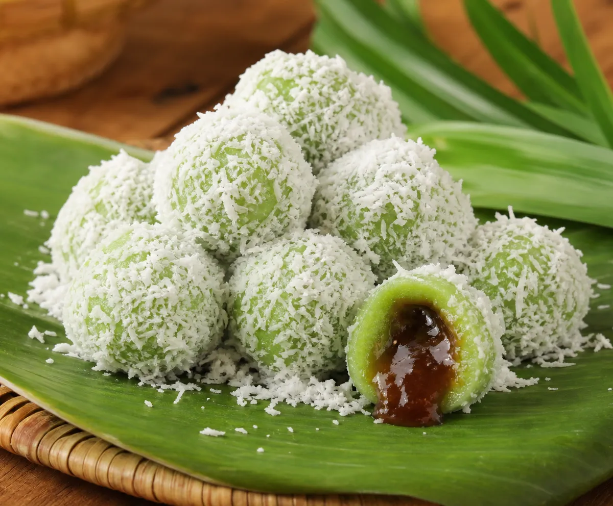 Green pandan klepon coated with grated coconut on a banana leaf