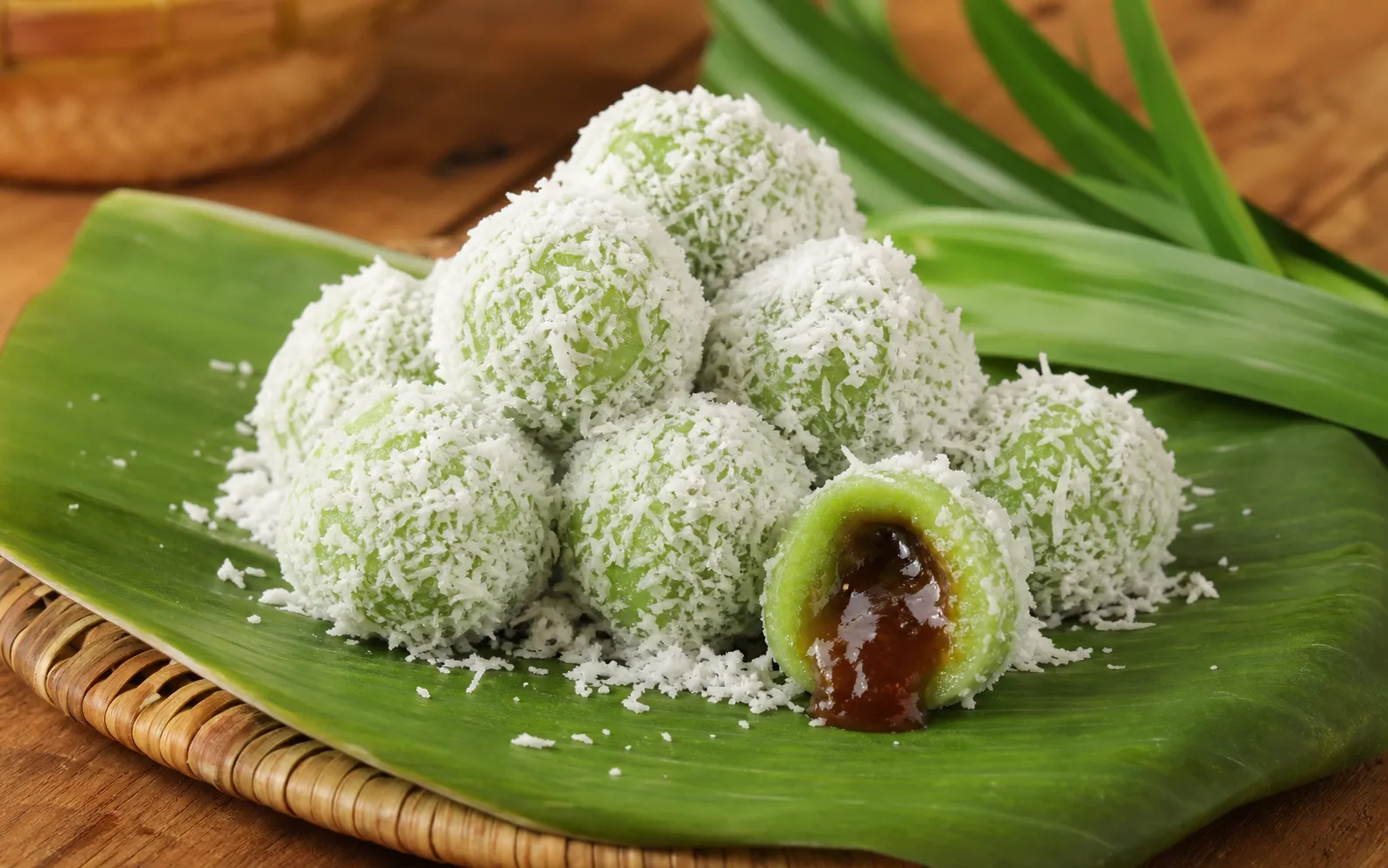 Green klepon rolled in grated coconut on a banana leaf